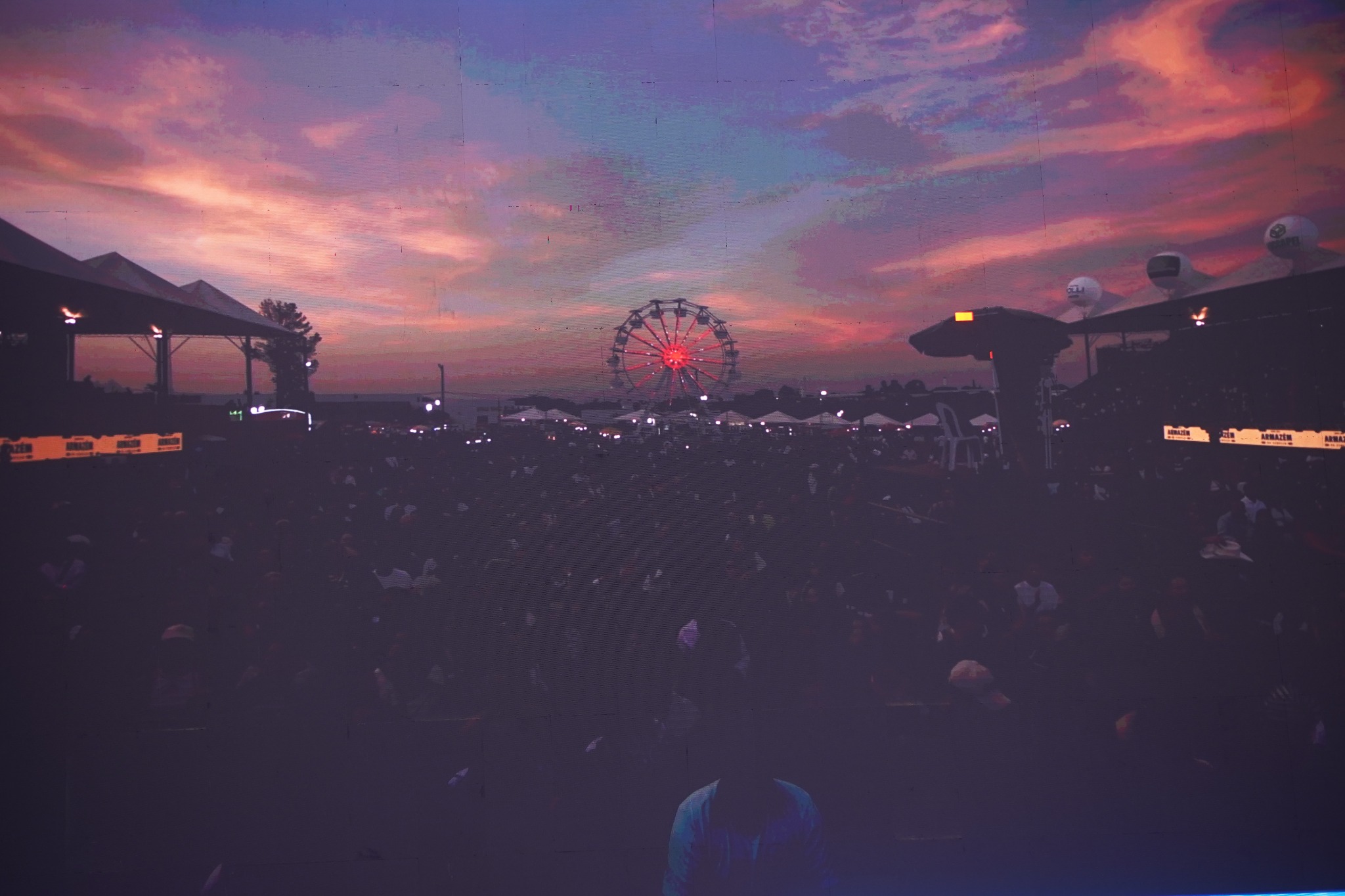 Público da Festa do Peão de Piracicaba ao entardecer com roda-gigante ao fundo